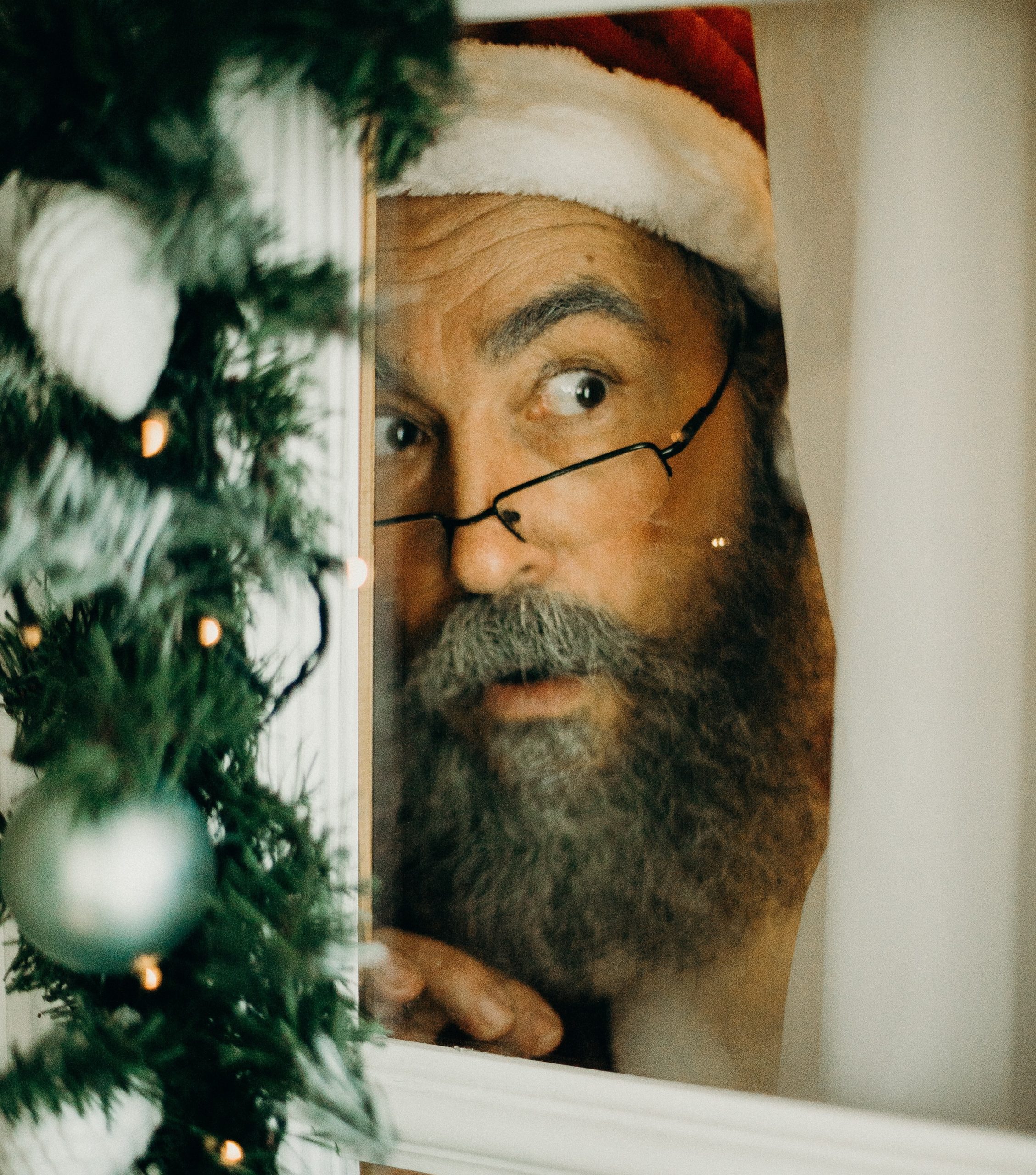 Closeup of Santa peeking out window from behind curtains